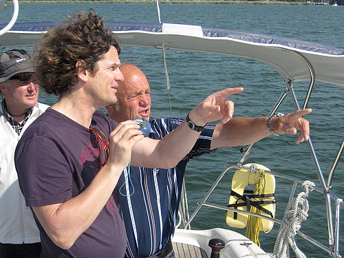 Drei Männer mit Kompass auf einem Segelboot